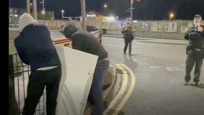 A PSNI officers appears to look on as loyalists steal a Saoradh poster 