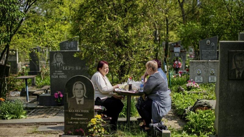 Vera Velakanova, left, and Lyudmila Vondarenko eat some food at the Kapustyanyy cemetery during the day that Ukrainians mark as the day of the dead, in Zaporizhzhia, Ukraine on Sunday May 1 2022. Zaporizhzhia is the destination for hundreds of displaced Ukrainians fleeing the besieged city of Mariupol PICTURE: Francisco Seco/AP 