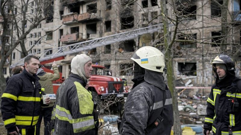 Ukrainian firefighters work in a resident building after it was hit by Russian artillery shelling in the capital Kyiv on Monday 