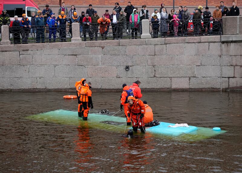 Emergency responders work to recover victims of a bus crash in St Petersburg, Russia (Dmitri Lovetsky/AP)