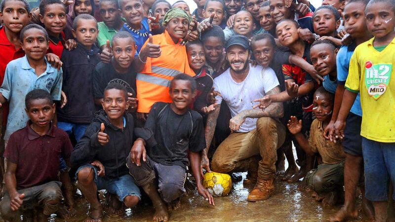 David Beckham with children in Kumnga Village, Papua New Guinea after playing game of football in the mud and rain. Pic by Jackie Nickerson 