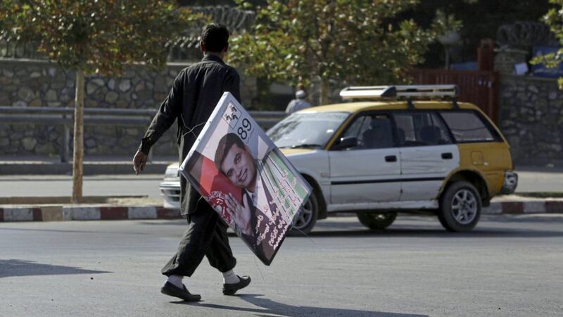 A man carries an election poster for parliamentary candidate Najeebullah Nasir during the first day of election campaigning in Kabul, Afghanistan. Picture by Rahmat Gul/AP 