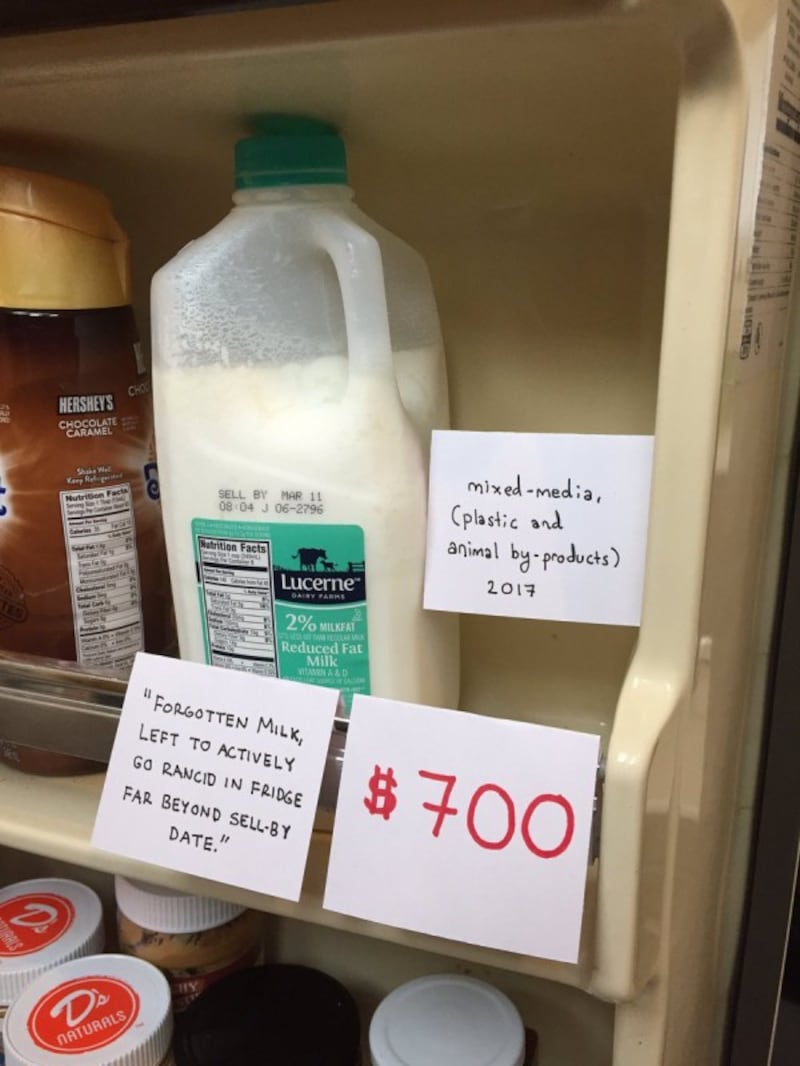 A milk carton with a price label and gallery signs