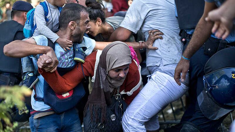 A woman gets trampled as refugees push through police lines in Tovarnik, Croatia, Thursday, September 17, 2015