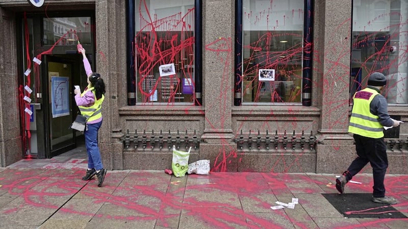 An Extinction Rebellion protestor smears Barclays Bank in Belfast with red paint, part of a UK-wide protest. 
