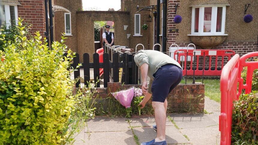 A man lays flowers at the scene in Bedfont (PA)