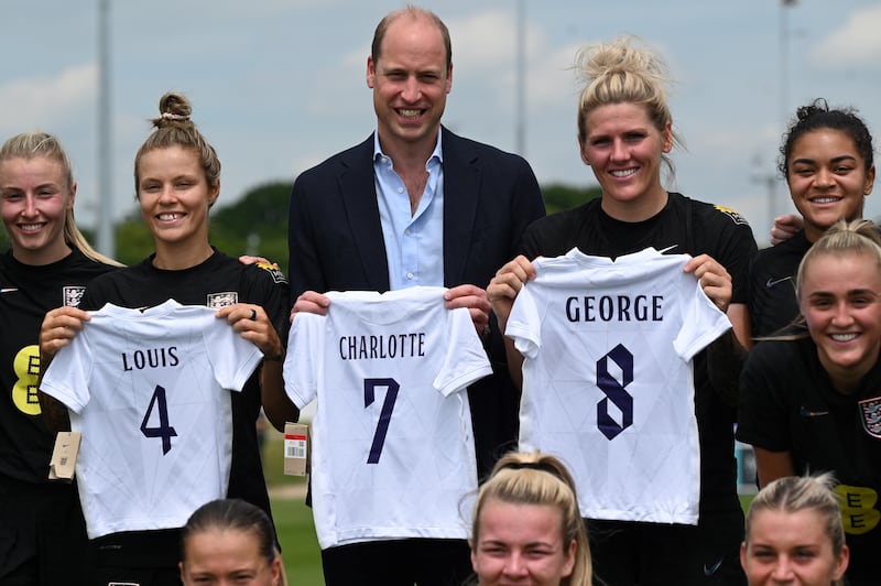 William with Daly, second left, and her England teammates holding football jersey bearing the names of his three children