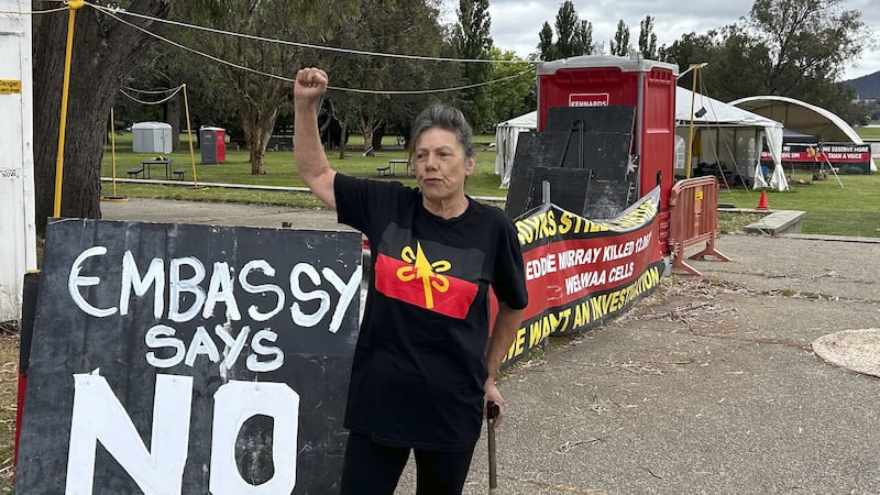 Indigenous activist Susanne Levy stands near a sign that opposes the referendum as Australians cast their final votes in Canberra (Rod McGuirk/AP)