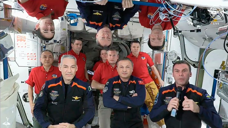 The 11 International Space Station crew members with, in blue, the Axiom Space 3 crew, Walter Villadei, Alper Gezeravci and Marcus Wandt. Above them hanging upside down in blue is Axiom Space’s Michael Lopez-Alegria (Nasa via AP)