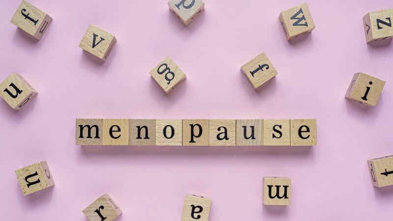 Menopause word on wooden block. Flat lay view on light pink background.. 