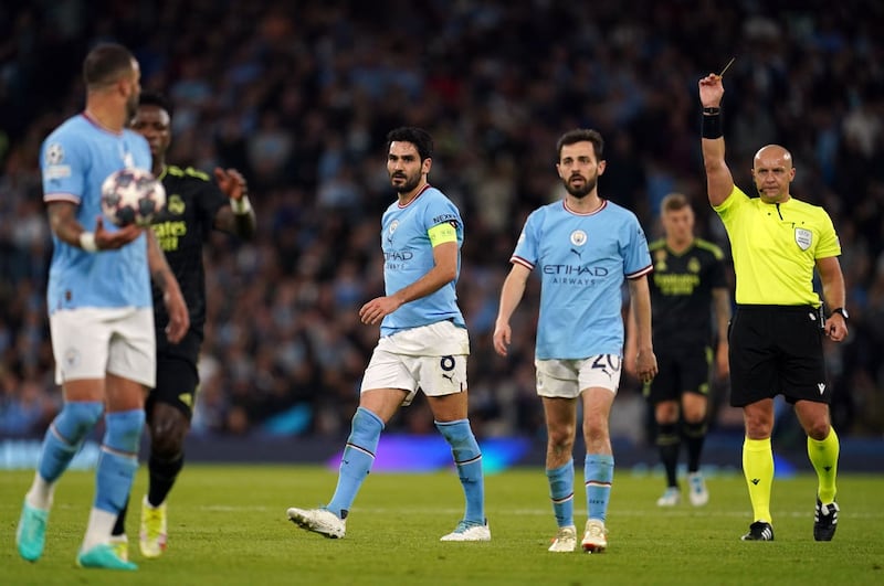Manchester City’s Ilkay Gundogan, centre, is shown a yellow card by referee Szymon Marciniak, right, during the Champions League semi-final second leg against Real Madrid
