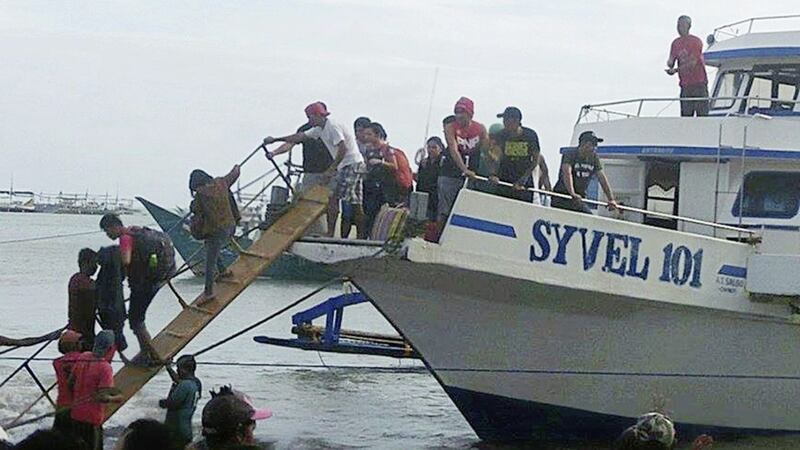 Rescued passengers from the ill-fated M/V Mercraft 3 disembark from a boat which helped in the rescue operation at Infanta township, Quezon province in northeastern Philippines PICTURE: DJ Kyle/AP 
