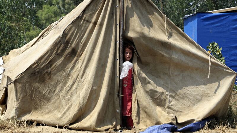 A displaced girl peers from the door of her tent after floodwaters hit her family home, in Charsadda, Pakistan, Wednesday, Aug. 31, 2022 (AP Photo/Mohammad Sajjad)