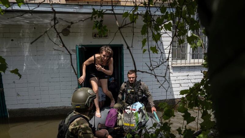 Ukrainian servicemen evacuate local residents from their flooded homes after the dam collapsed (Evgeniy Maloletka/AP)