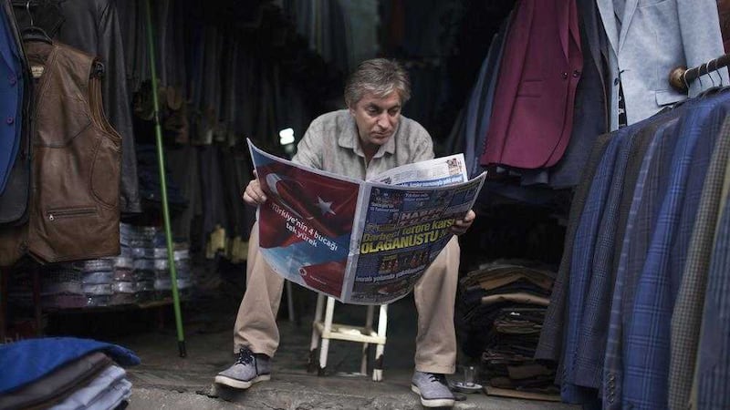 A shop owner reads a newspaper in Istanbul, yesterday. Picture by Petros Giannakouris/AP 