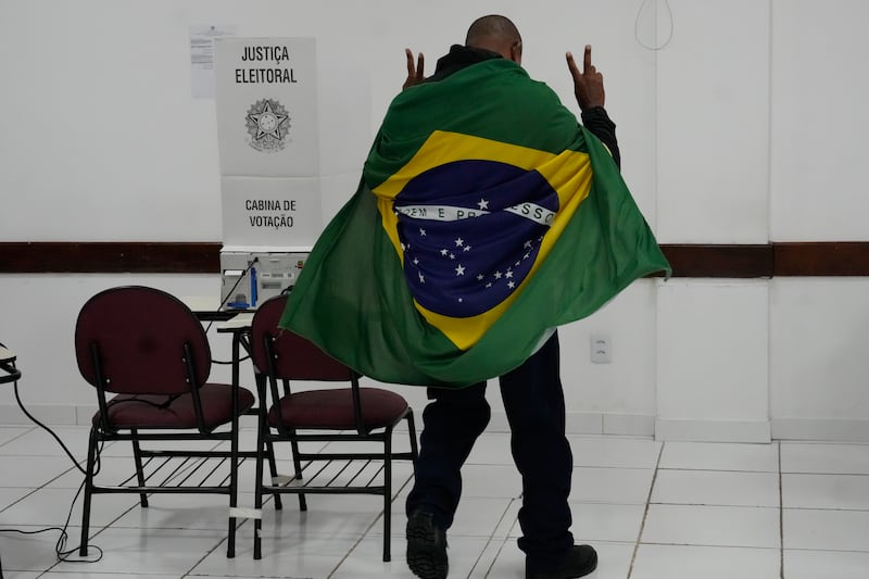 A man wrapped in a Brazilian flag arrives to vote in Brasilia (Eraldo Peres/AP)