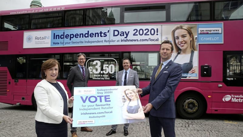 ON THE BUSES: Launching the initiative to support independent retailers and the high streets, in front of one of the Translink buses carrying the message, are economy minister Diane Dodds with (from left) Glyn Roberts (Retail NI), John Brolly (Irish News) and Gareth Burnside (Camelot) 