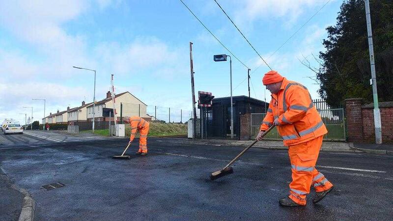 Railway workers clear debris in Lurgan after petrol bombs were thrown at police and a van was set alight 