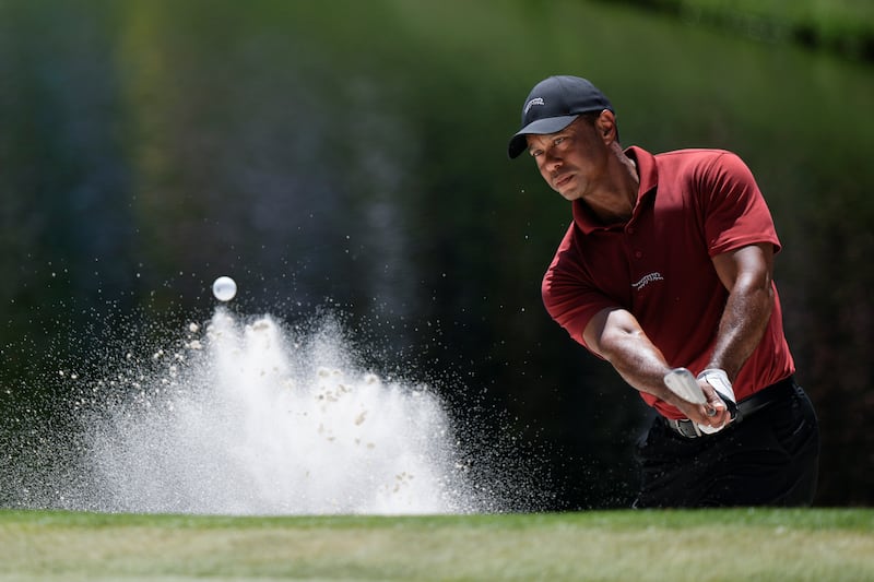 Tiger Woods hits from the bunker on the 16th hole during his 100th round in the Masters (Charlie Riedel/AP)