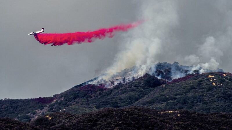 A plane drops fire retardant as firefighters continue to battle a wildfire in the Cleveland National Forest near Corona, California Picture by AP 