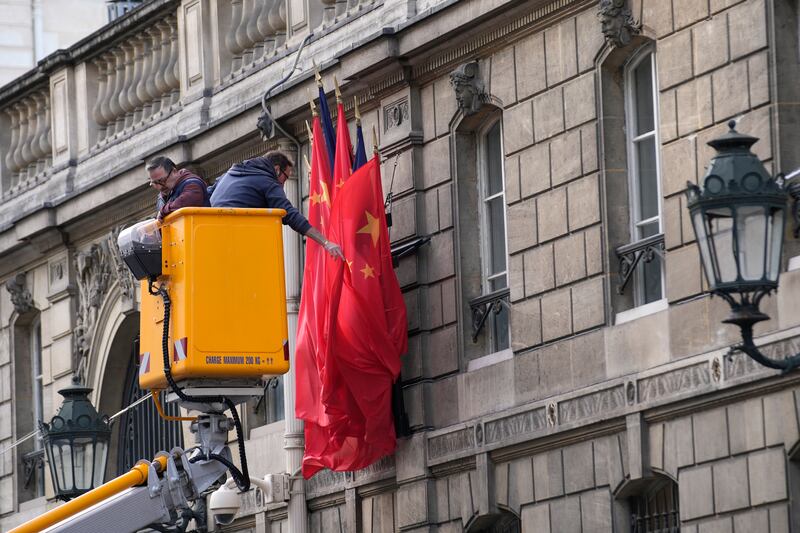 Workers instal French and Chinese flags on the facade of the Elysee Palace (AP)