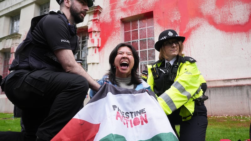 Police officers detain a person after members of Youth Demand threw red paint over the outside of the Ministry of Defence building in London