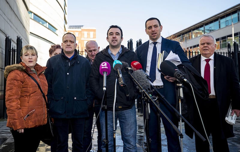 Aaron McCone (son of John Harbinson, 2nd left), Joe Convie (father of Gary Convie, 3rd left behind), look on as Keiran Fox (son of Eamon Fox, centre) speaks to the media with solicitor Padraig O'Muirigh (2nd right) and SDLP MLA John Dallas (right) outside Laganside Court in Belfast after Gary Haggarty was sentenced to six and a half years for 202 terror offences&nbsp;