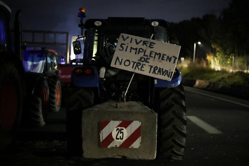 A sign on a tractor reads ‘live simply from our work’ at a highway barricade in Aix-en-Provence, southern France (AP Photo/Daniel Cole)