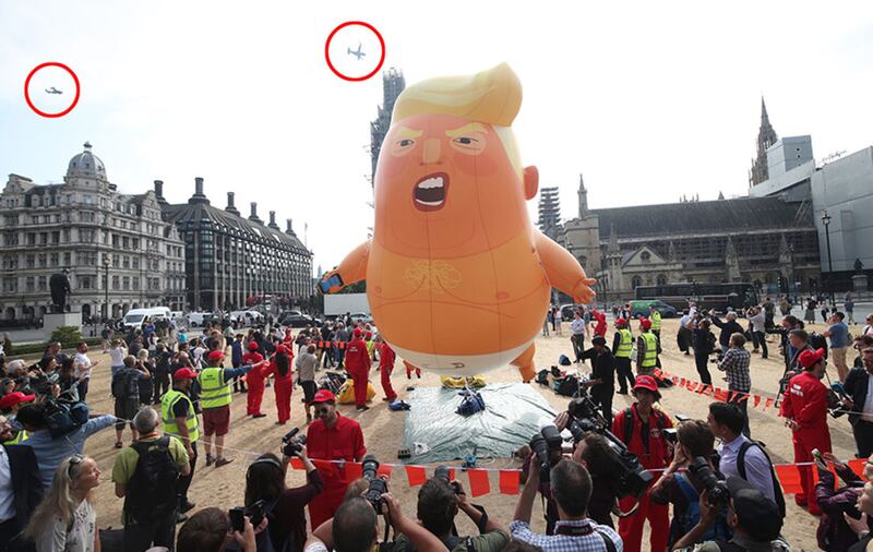 US Marine helicopters (ringed), which are used by the presidential entourage, pass the 'Baby Trump' balloon as it rises after being inflated in London's Parliament Square, as part of the protests against the visit of US President Donald Trump to the UK&nbsp;