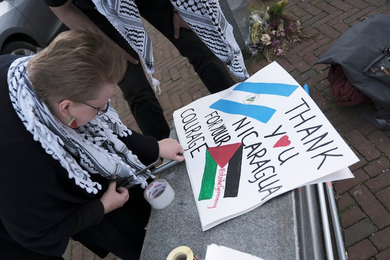 A pro-Palestinian activist works on a protest poster near the International Court of Justice, or World Court, in The Hague, Netherlands (Patrick Post/AP)