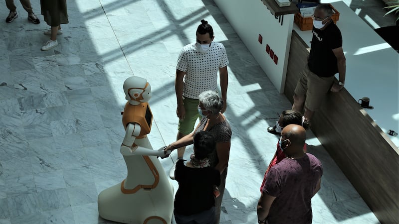A SPRING robot standing alongside people in a hospital.