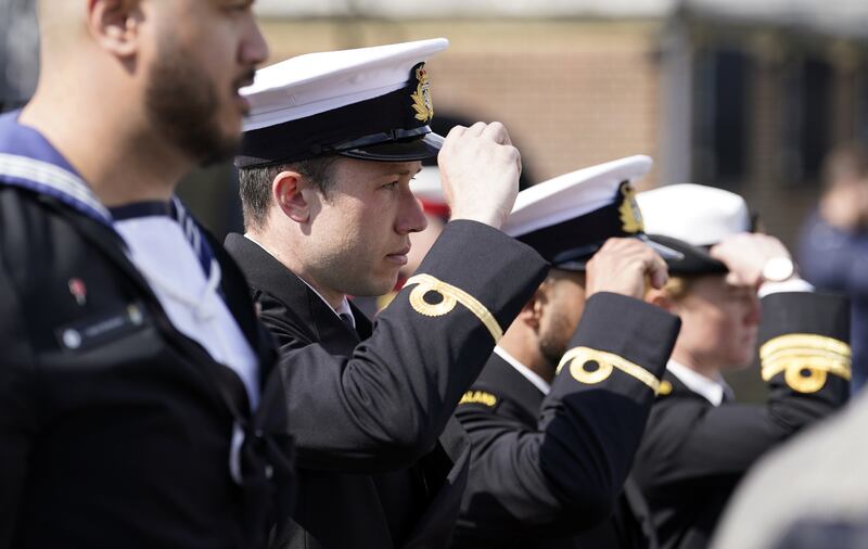 Members of the Royal New Zealand Navy replace their caps during an Anzac Day service of remembrance on board HMS M.33