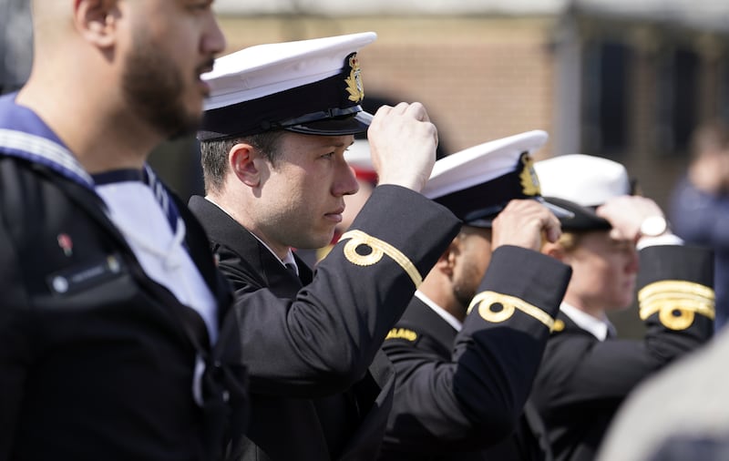 Members of the Royal New Zealand Navy replace their caps during an Anzac Day service of remembrance on board HMS M.33