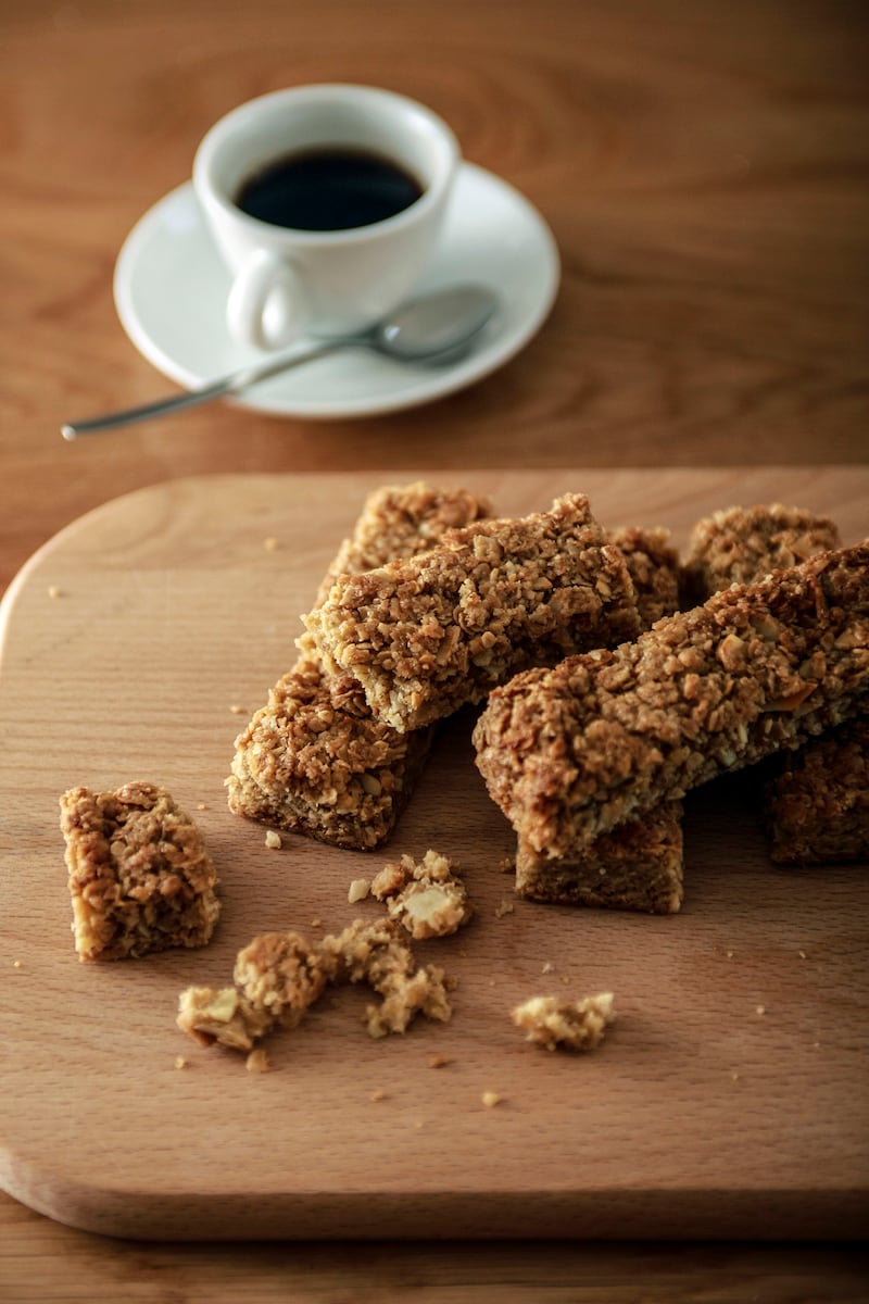 Oatmeal flap jacks on a wooden board with an espresso in the background.