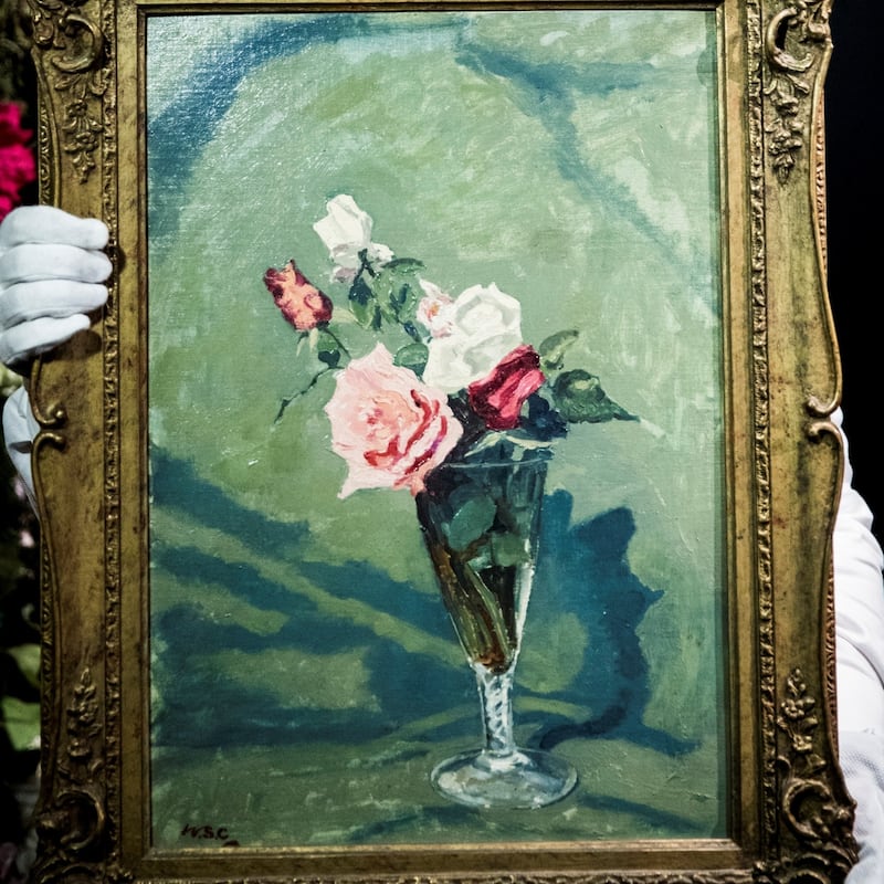 Sir Winston Churchill's painting Roses In A Glass Vase is held up for display (Sotheby's)