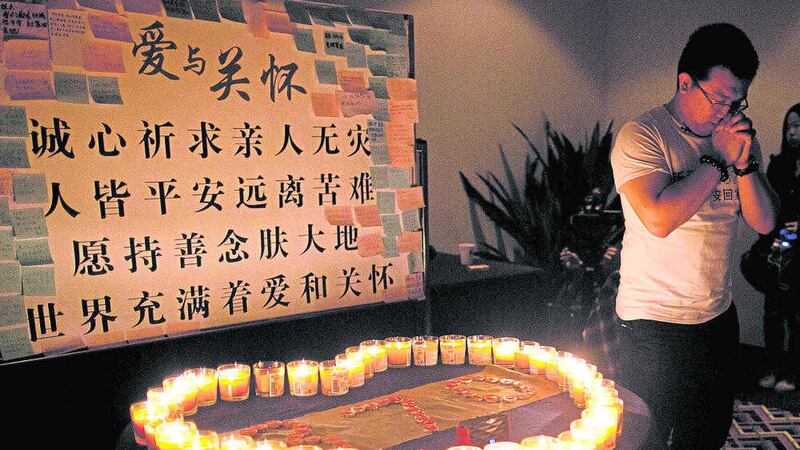 A man, one of the relatives of Chinese passengers on board Malaysia Airlines Flight 370, prays near candles in Beijing 