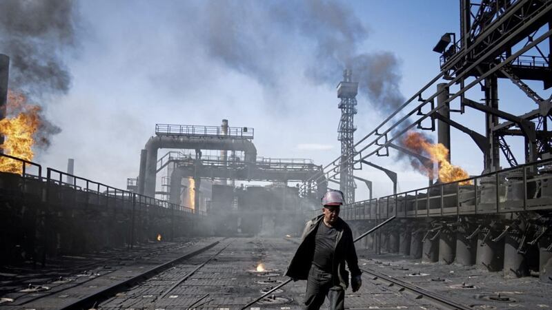 A worker, pictured in 2015, carries a metal rod at the front-line Avdiivka coking plant in eastern Ukraine Picture by AP 