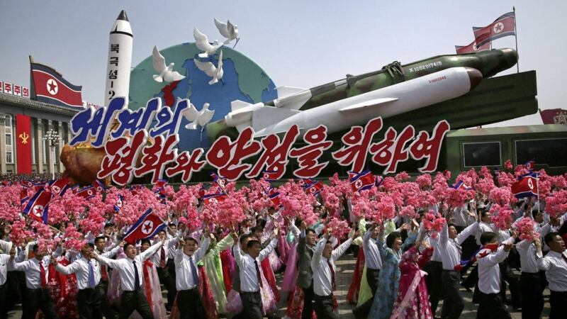 North Korean men and women wave flags and plastic flowers as a float with model missiles and rockets with words that read &#39;For Peace and Stability in the World&#39; is paraded across Kim Il-sung Square during a military parade in Pyongyang Picture by Wong Maye-E 