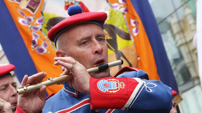 Photograph mainly in blue and red of flute player at an Oranage march