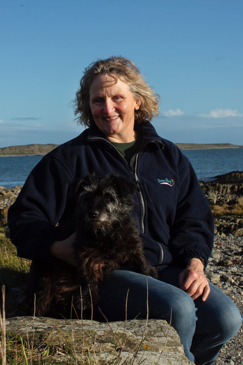 Writer Roisin Maguire sitting on a sea wall with her dog