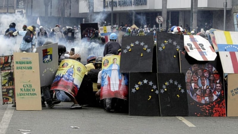 Protesters form a human barricade, some using homemade shields decorated with digital renderings of religious and national symbols created by artist Oscar Olivares, during a protest in Caracas, Venezuela. earlier this month. Picture: Fernando Llano/AP 