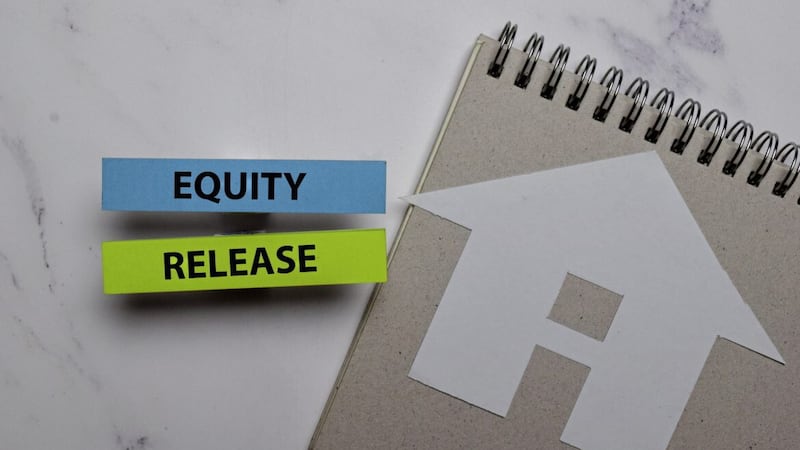 Equity Release write on sticky note and house made from paper isolated on Office Desk. Retirement concept 