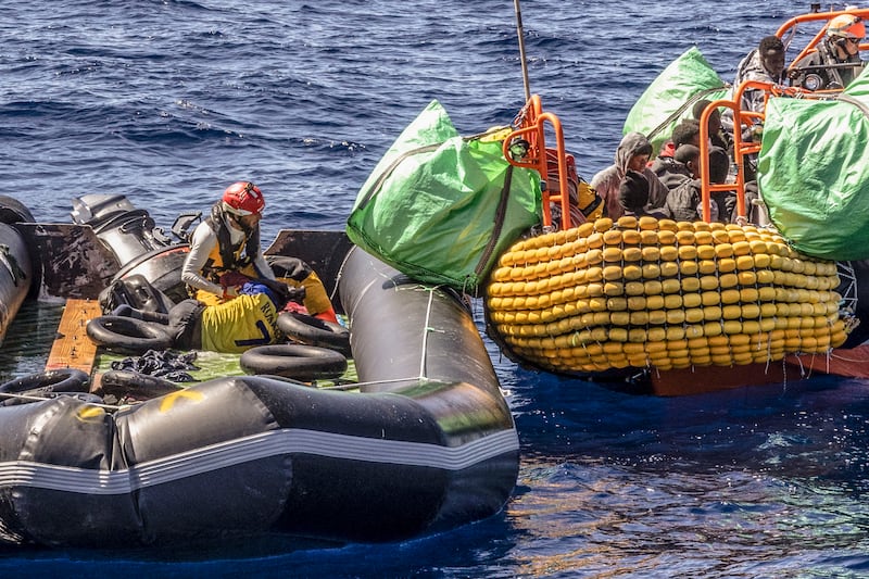 A migrant is helped to evacuate a partially deflated rubber dinghy by the rescue personnel of the SOS Mediterranee humanitarian ship Ocean Viking in the Mediterranean on Wednesday (Johanna de Tessieres/SOS Mediterranee via AP)