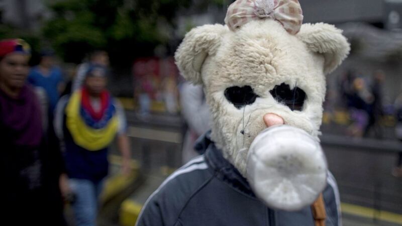 A demonstrator wearing a makeshift gas mask fashioned with the head of a teddy bear, takes part in an anti-government protest in Caracas, Venezuela Picture by Ariana Cubillos/AP 