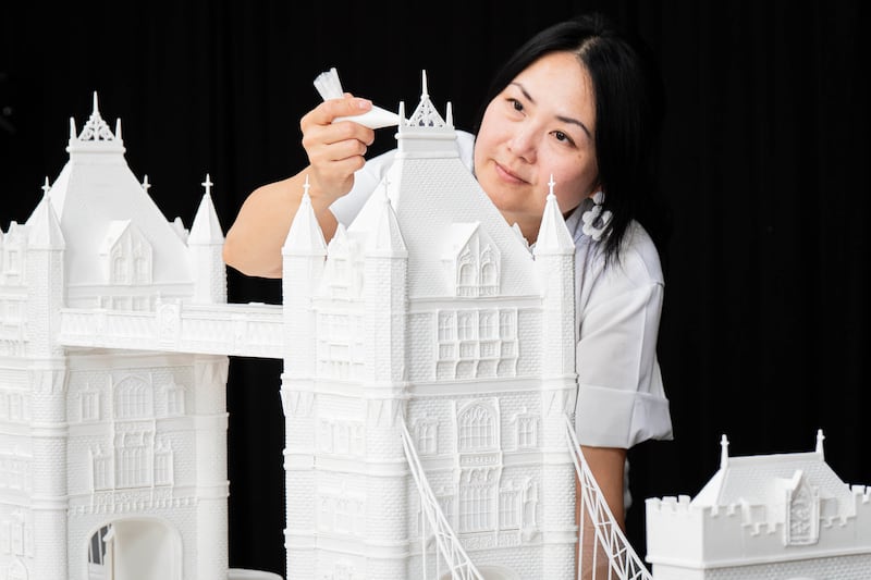 Woman pipes icing sugar onto Tower Bridge sugar sculpture