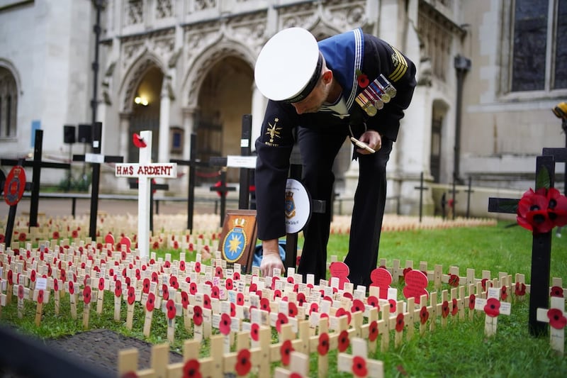 A member of the Royal Navy places a memorial cross at the Field of Remembrance, in its 95th year, at Westminster Abbey in London