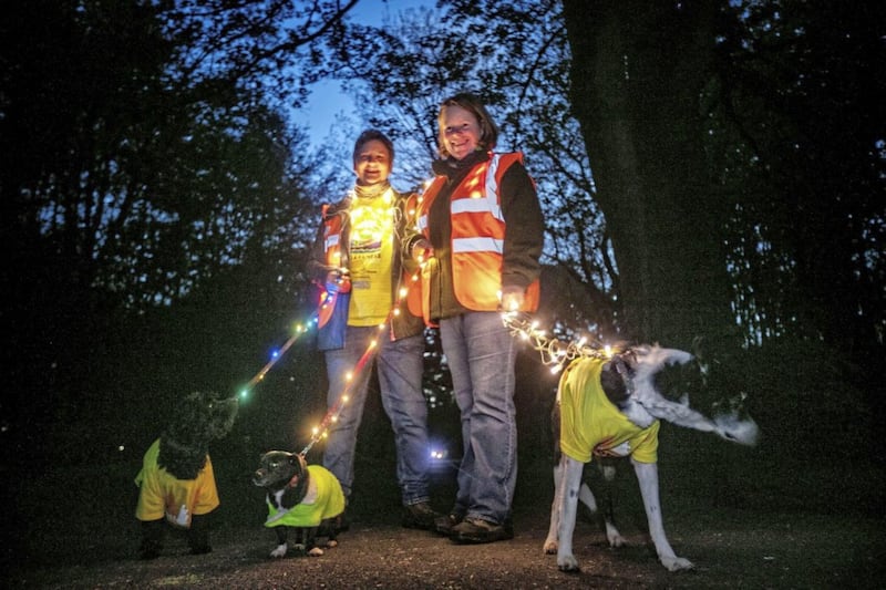 Two people walking their dogs through Ormeau Park in Belfast during the Darkness Into Light event. The event was organised by Pieta House and supported by Electric Ireland