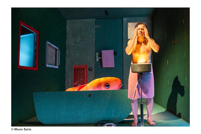 A scene from the children's theatre piece I .. Um I with a man washing his face and a giant goldfish in his bathtub