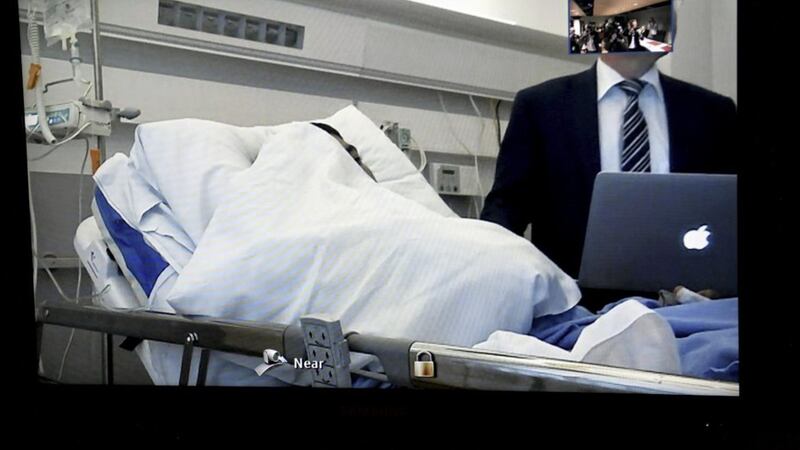 Seen on a court video link screen, Moroccan man Abderrahman Mechkah, lays in a hospital bed during the initial remand hearing, on suspicion of murder, attempted murder, and terrorism crimes, at court in Turku, Finland on Tuesday. Picture by Martti Kainulainen/Lehtikuva via Associated Press. 