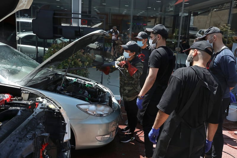Maryam Roohani, left, cleans a car as her trainees watch, at a detailing shop in Tehran, Iran